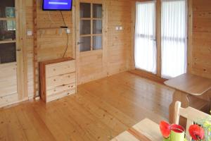 a living room with a tv and a wooden floor at Bungalow, Wrzosowo in Wrzosowo