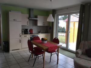 a kitchen with a table and red chairs and a kitchen with a table at Ferienhaus Pirol am Vilzsee in Mirow in Mirow