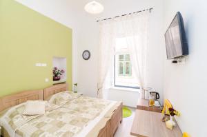1 dormitorio con 1 cama, TV y ventana en Rooms Tezoro, en Dubrovnik