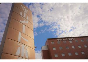 un edificio alto junto a un edificio con cielo en Moriyama Art Hotel en Moriyama