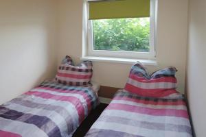 2 camas en una habitación con ventana en Holiday House in Szczecin at the lake with parking space for 4 persons, en Szczecin