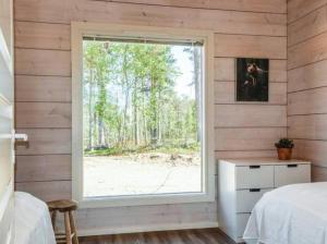 a bedroom with a window in a wooden wall at Villa Paatari, Inari (Paadarjärvi) in Inari +100 photos