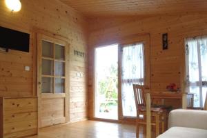 a room with wooden walls and a bedroom with a bed and a window at Bungalow, Wrzosowo in Wrzosowo