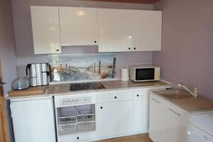 a kitchen with white cabinets and a sink and a microwave at holiday home, Kolczewo in Kołczewo