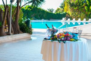 a table with wine glasses and flowers on it next to a pool at Hotel Dei Pini in Porto Empedocle