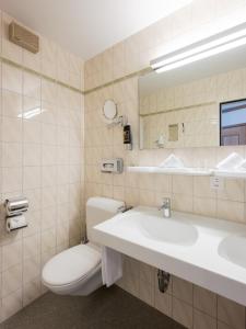 a bathroom with a sink and a toilet and a mirror at Ambassador Self Check-in Hotel in Lucerne