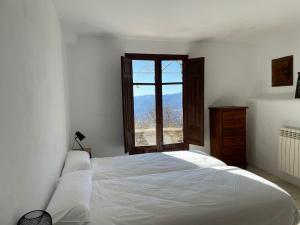 a white bedroom with a large bed and a window at Apartamentos El Cabo in Mairena