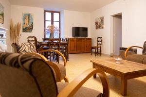 ein Wohnzimmer mit Stühlen, einem Tisch und einem TV in der Unterkunft Gîte de Grailhes in Aguessac