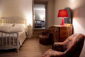 een slaapkamer met een bed, een lamp en een stoel bij Gîte de Grailhes in Aguessac