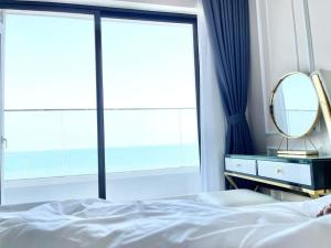 Schlafzimmer mit einem Bett, einem Spiegel und einem Fenster in der Unterkunft NHÀ TUI Share Quy Nhơn Serviced Apartment in Quy Nhon