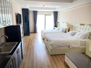 ein Schlafzimmer mit 2 Betten und einem Waschbecken sowie eine Küche in der Unterkunft NHÀ TUI Share Quy Nhơn Serviced Apartment in Quy Nhon