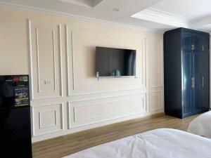 Schlafzimmer mit einem TV an der Wand und einem Bett in der Unterkunft NHÀ TUI Share Quy Nhơn Serviced Apartment in Quy Nhon