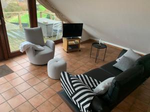 ein Wohnzimmer mit einem Sofa, Stühlen und einem TV in der Unterkunft FeWoFahrdorf in Fahrdorf