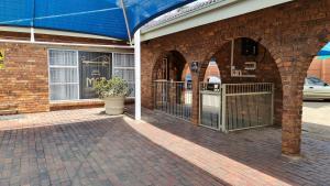 a brick building with a blue awning on a street at MFT GUEST HOUSE in Boksburg