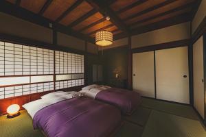 una camera con due letti in una stanza con soffitto di 古民家宿るうふ 蔦之家 a Koshu