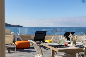 una mesa y sillas en un patio con vistas al océano en La Maison sur la Plage, en Calcatoggio