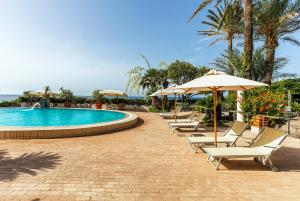 a row of chairs and umbrellas next to a swimming pool at Hotel Parco Smeraldo Terme in Ischia