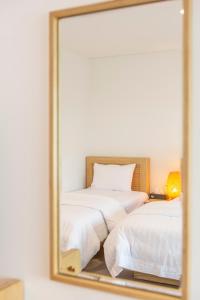 a white bed sitting in a bedroom next to a mirror at Lunamar Pension in Jeju