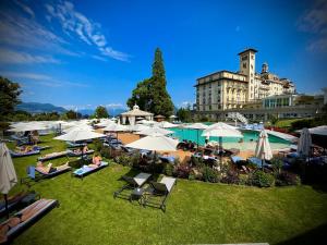 a group of people sitting on the grass with umbrellas at Grand Hotel des Iles Borromées & SPA in Stresa