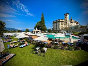 un gruppo di persone sedute sull'erba con ombrelli di Grand Hotel des Iles Borromées & SPA a Stresa