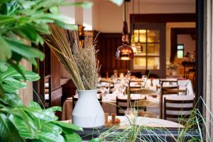 a table with a white vase with plants on it at Hotel & Restaurant Linde in Münstertal
