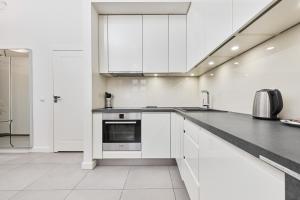 kuchnia z białymi szafkami i blatem w obiekcie City Center Railway Station Apartment Piłsudskiego by Noclegi Renters we Wrocławiu