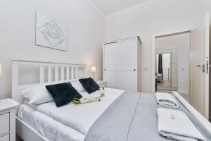 biała sypialnia z dużym białym łóżkiem i lustrem w obiekcie City Center Railway Station Apartment Piłsudskiego by Noclegi Renters we Wrocławiu