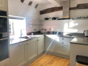 a kitchen with white cabinets and a sink and a window at 3 The Olde Barn Apartments in Stamford