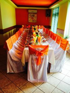 a long table set up for a banquet with orange bows at Pension Popas Paradis in Buziaş