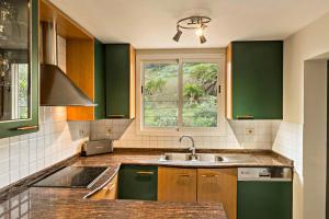 a kitchen with green cabinets and a sink and a window at El Jardín de Santa Bígida in Santa Brígida
