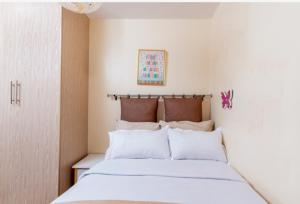a bedroom with a bed with white sheets and pillows at Westpoint Suites by Senga in Nairobi +23 photos