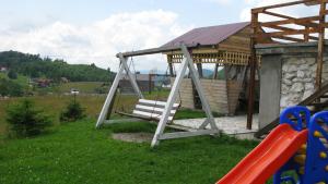 a swing set in a yard with a house at Pensiunea Pui de Urs Sirnea in Fundata