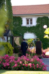 a man standing in front of a house with flowers at Relais de Margaux - Hôtel & Spa in Margaux