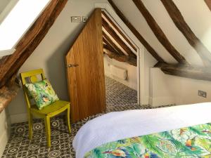 a attic bedroom with a bed and a chair at 3 The Olde Barn Apartments in Stamford