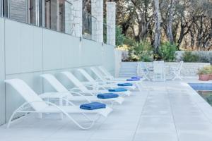 a row of white chairs sitting next to a pool at Villa Breeze & Villa Coco by Konnect, Avlaki Beach in Kassiopi