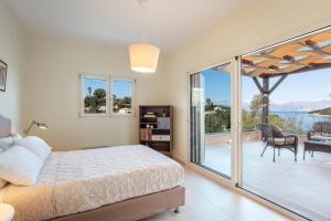 a bedroom with a bed and a balcony with a view at Villa Breeze & Villa Coco by Konnect, Avlaki Beach in Kassiopi