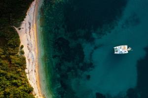 a boat in the water next to a beach at Villa Breeze & Villa Coco by Konnect, Avlaki Beach in Kassiopi