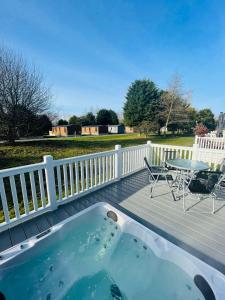 a hot tub on a deck with a table and chairs at Brians Lodge with Hot Tub in Pocklington