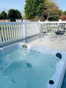 a hot tub on a deck with a table and chairs at Brians Lodge with Hot Tub in Pocklington
