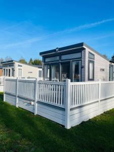 a mobile home with a white fence in the grass at Brians Lodge with Hot Tub in Pocklington