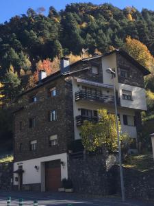 a building on a hill with a tree at Apartament turistic Pont d’Ordino in La Massana