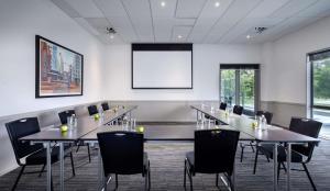 a conference room with tables and chairs and a screen at Rydges Latimer Christchurch in Christchurch
