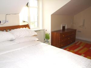 a bedroom with a white bed and a dresser at Glendalough Scenery Farmhouse in Roundwood
