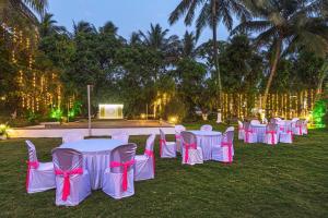 a row of tables with pink and white chairs at SaffronStays Serene Retreat, Alibaug in Alibaug