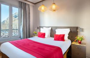 una camera da letto con un grande letto bianco con cuscini rossi di Hotel Eiffel Segur a Parigi