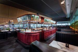 a restaurant with red walls and tables and benches at Rydges Wellington Airport in Wellington