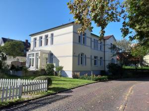 a white house with a white picket fence at Ferienwohnung Villa im Park in Wangerooge