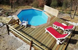 eine Terrasse mit einem Pool und 2 Stühlen in der Unterkunft Chalet sur pilotis avec piscine privée in Lucéram