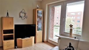 - un salon avec une télévision et une grande fenêtre dans l'établissement "Ferienresidenz Kormoran" Appartement KOR28, à Döse