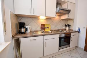 a small kitchen with white cabinets and a sink at Haus "Luv und Lee" Appartement LEE01 in Döse